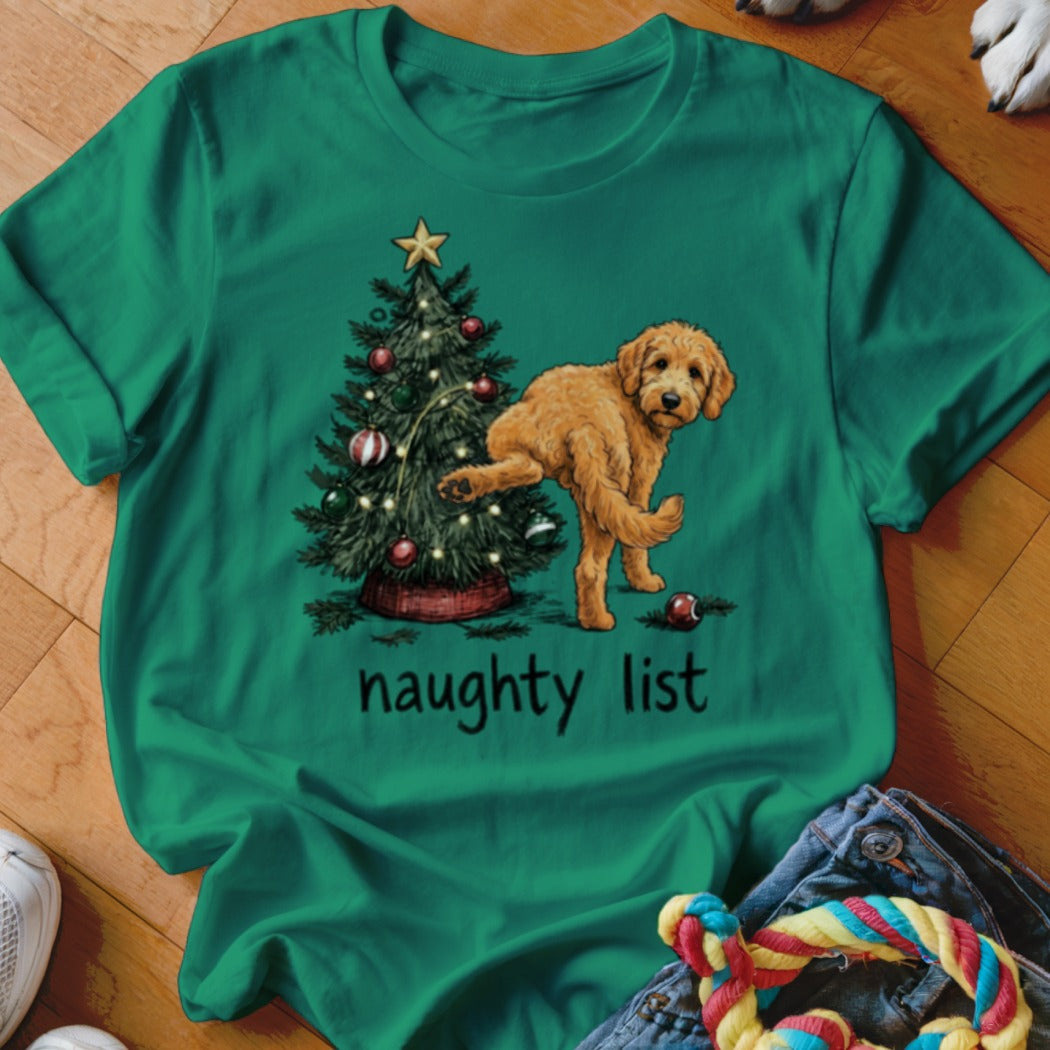 Green t-shirt with a goldendoodle near a Christmas tree, text reads "naughty list."