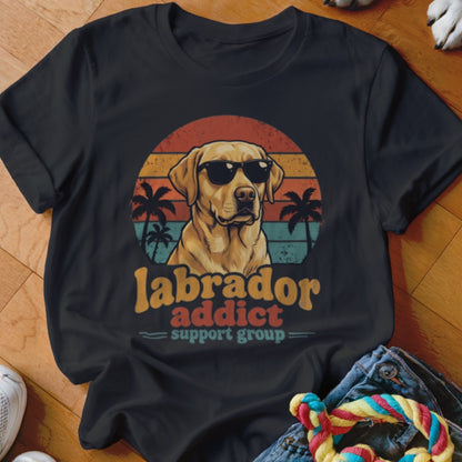 A black t-shirt features a graphic of a yellow Labrador wearing sunglasses in front of a sunset, with text reading Labrador Addict Support Group.
