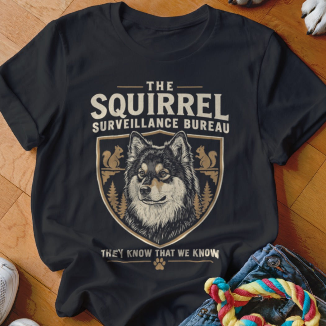 Black t-shirt featuring a graphic of a dog inside a crest with squirrel illustrations and text that reads The Squirrel Surveillance Bureau.