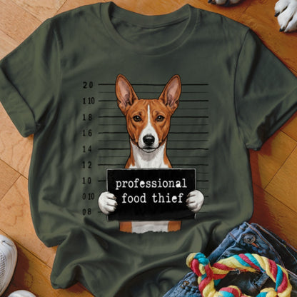 Basenji dog in mugshot holding "professional food thief" sign.