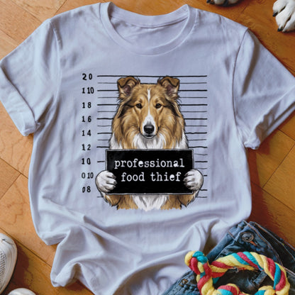 White t-shirt graphic of a collie holding a "professional food thief" sign with a mugshot background.