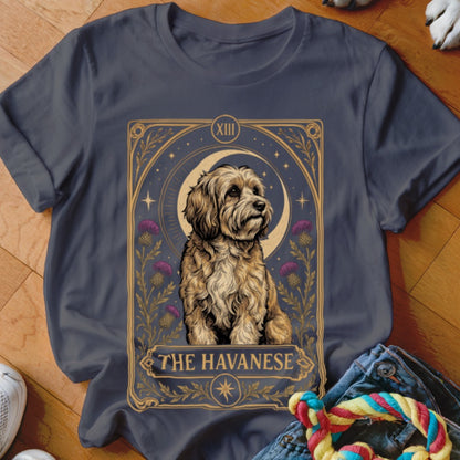 A dark gray t-shirt featuring a tarot card design of a Havanese dog, crescent moon, and purple thistles.