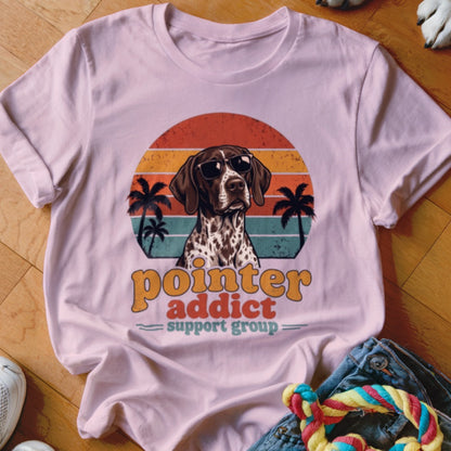Light pink t-shirt featuring a retro graphic of a German Shorthaired Pointer wearing sunglasses with sunset and palm tree background.