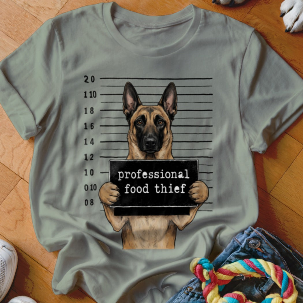 German Shepherd in mugshot with sign reading "professional food thief."