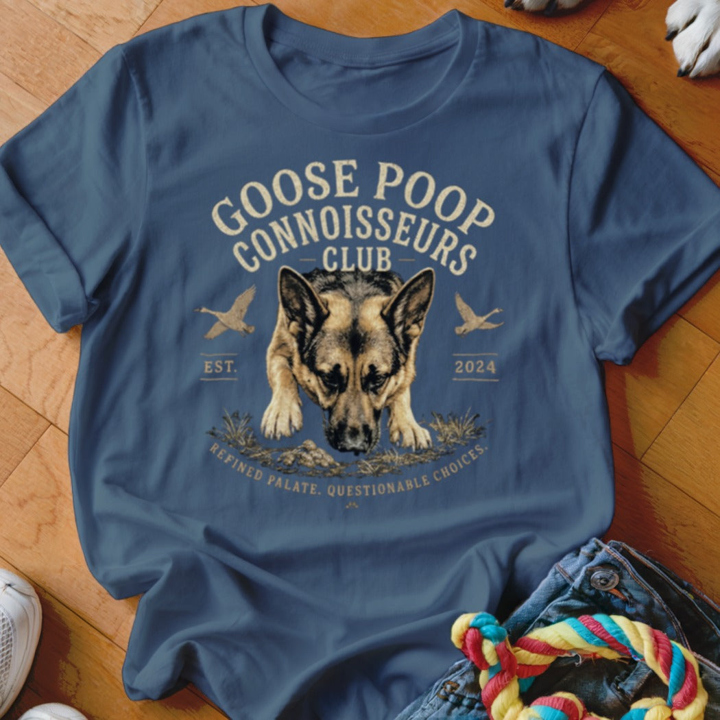 German Shepherd wearing a t-shirt that reads "Goose Poop Connoisseurs Club".