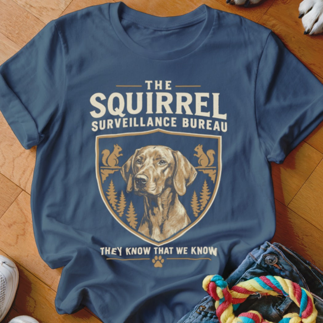 Blue t-shirt featuring a graphic of a dog and squirrels with the text The Squirrel Surveillance Bureau.