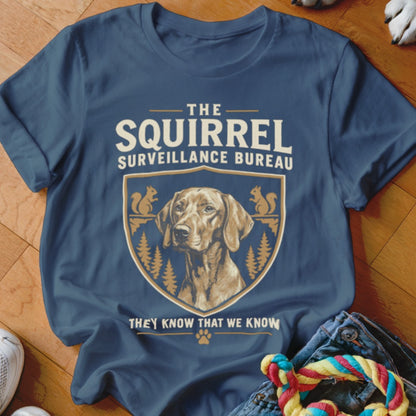 Blue t-shirt featuring a graphic of a dog and squirrels with the text The Squirrel Surveillance Bureau.