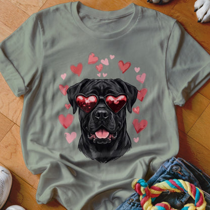 Sage green t-shirt featuring a graphic of a black dog wearing red heart-shaped sunglasses, surrounded by pink hearts.
