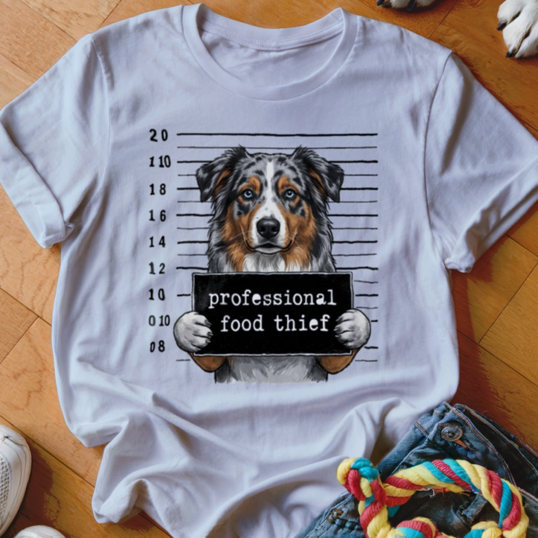 Australian Shepherd in mugshot holding sign "professional food thief."