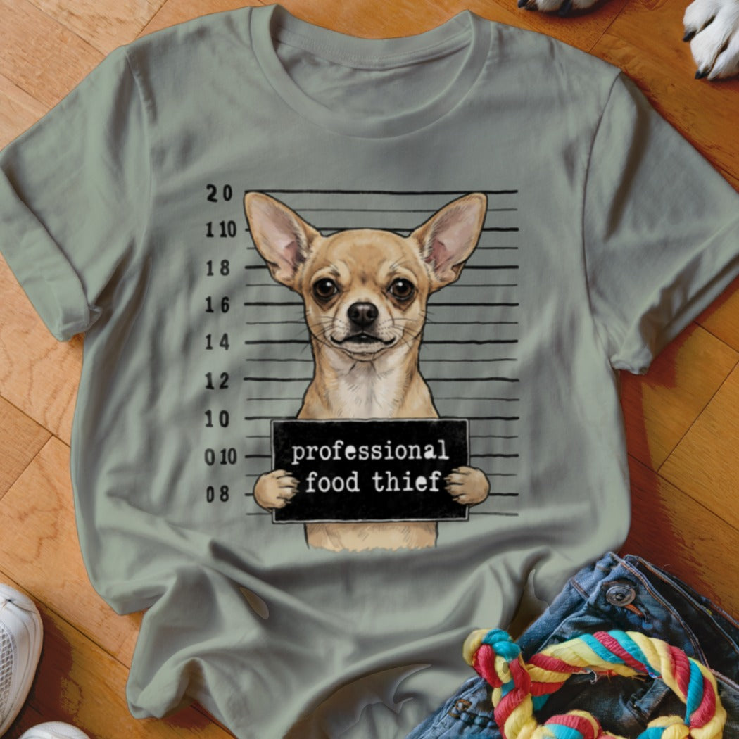 Chihuahua mugshot with "professional food thief" sign on a light green t-shirt.