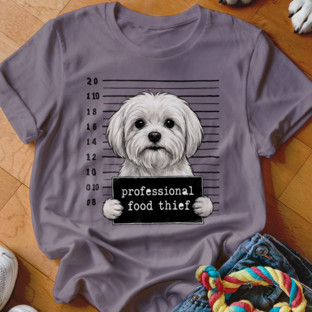 White dog in mugshot with "professional food thief" sign.