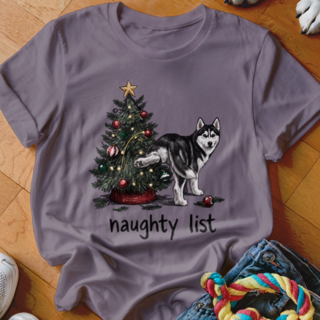 A grey t-shirt featuring a graphic of a husky dog peeing on a Christmas tree with text reading "naughty list".