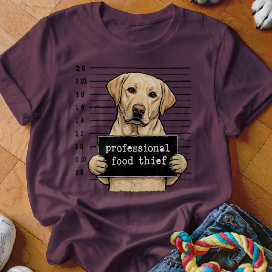 Yellow lab mugshot with "professional food thief" sign on a maroon t-shirt.