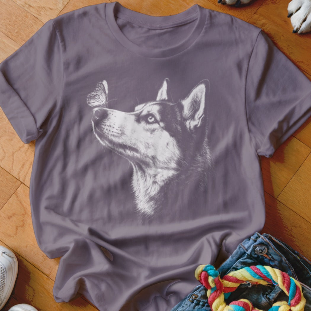A dark purple t-shirt printed with a white sketch of a husky dog looking at a butterfly.
