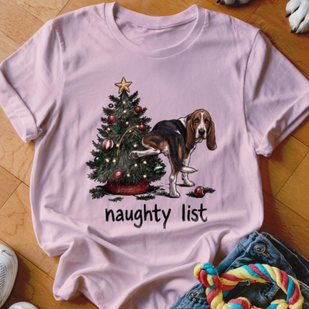 Basset hound with leg raised near Christmas tree, text reads "naughty list".