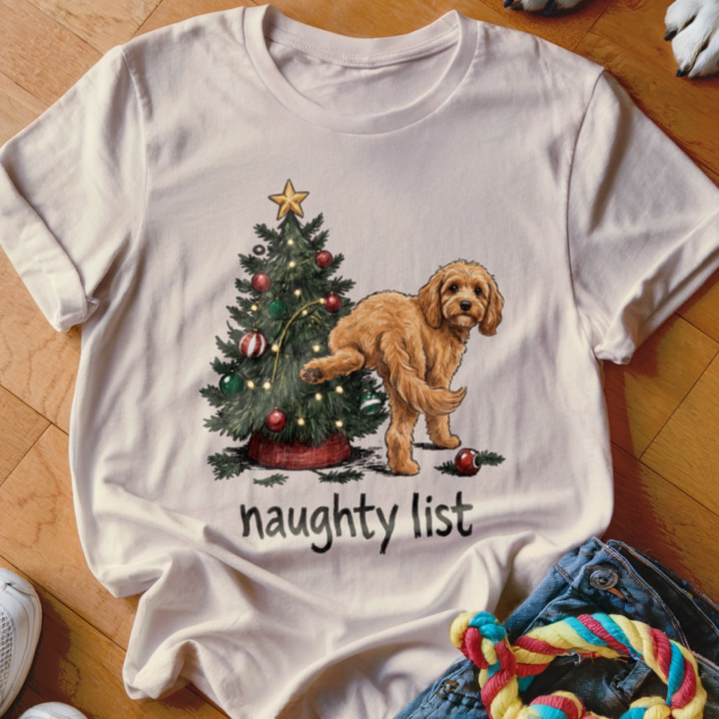 White t-shirt with Christmas tree and golden dog illustration, text "naughty list".