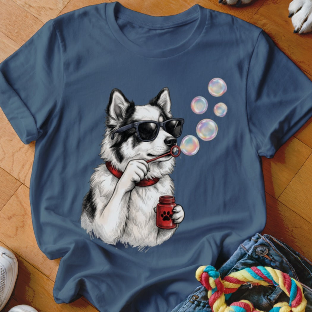 Blue t-shirt featuring an illustration of a black and white dog wearing sunglasses and blowing bubbles.