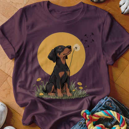 A purple crewneck t-shirt featuring an illustration of a puppy blowing dandelion seeds against a yellow moon background.