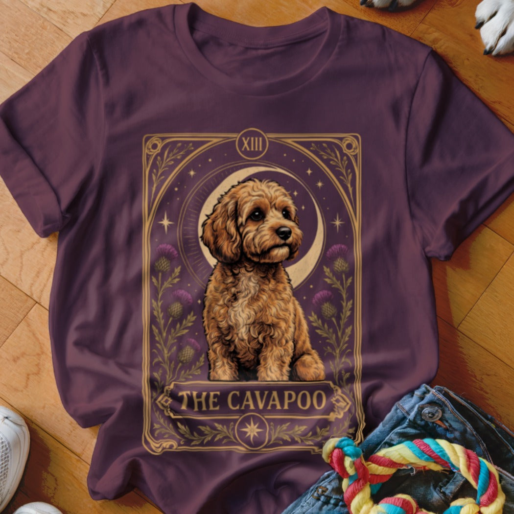 A dark purple t-shirt features a tarot card design with a fluffy brown Cavapoo dog.