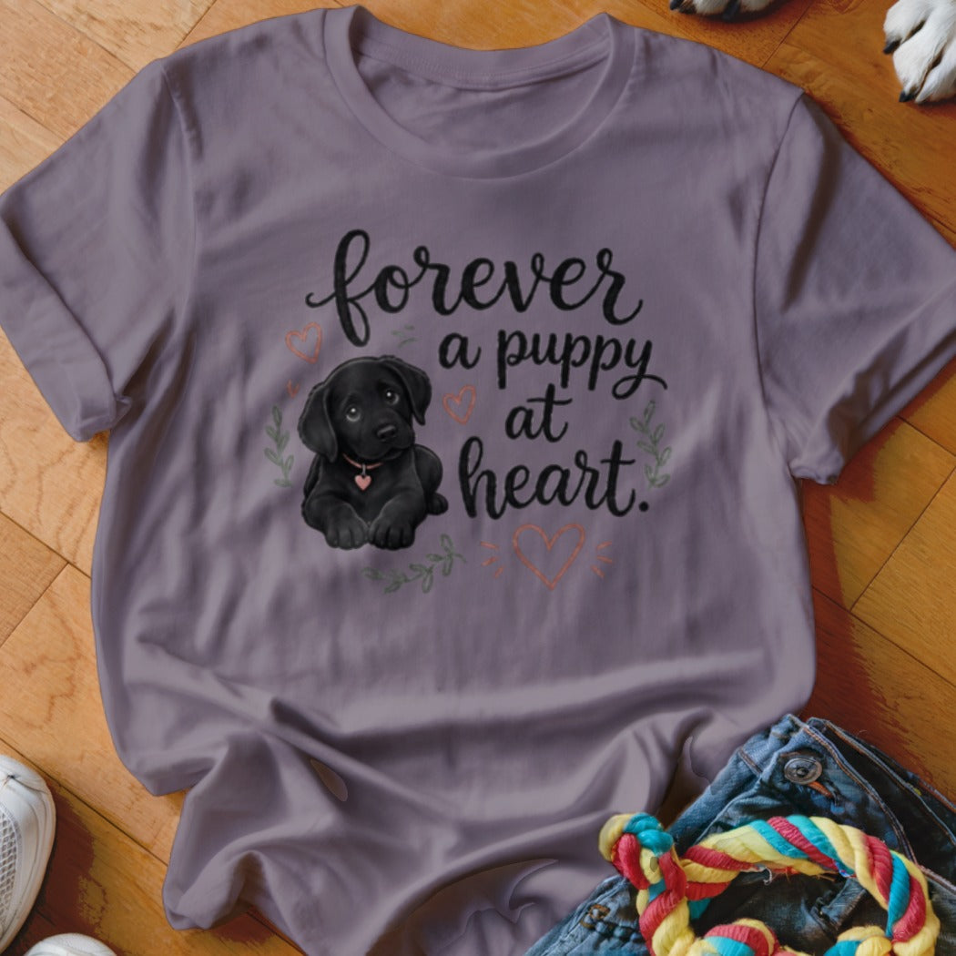 Purple t-shirt with illustration of a black puppy and text "forever a puppy at heart."