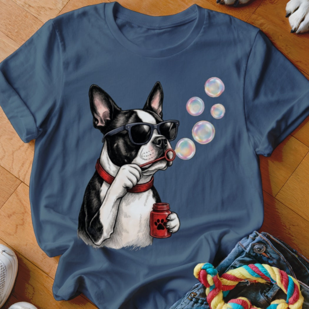 A blue crew-neck t-shirt featuring a graphic of a Boston Terrier wearing sunglasses and blowing soap bubbles.