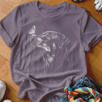 A purple short-sleeved t-shirt featuring a white graphic of a Rottweiler looking up at a butterfly.
