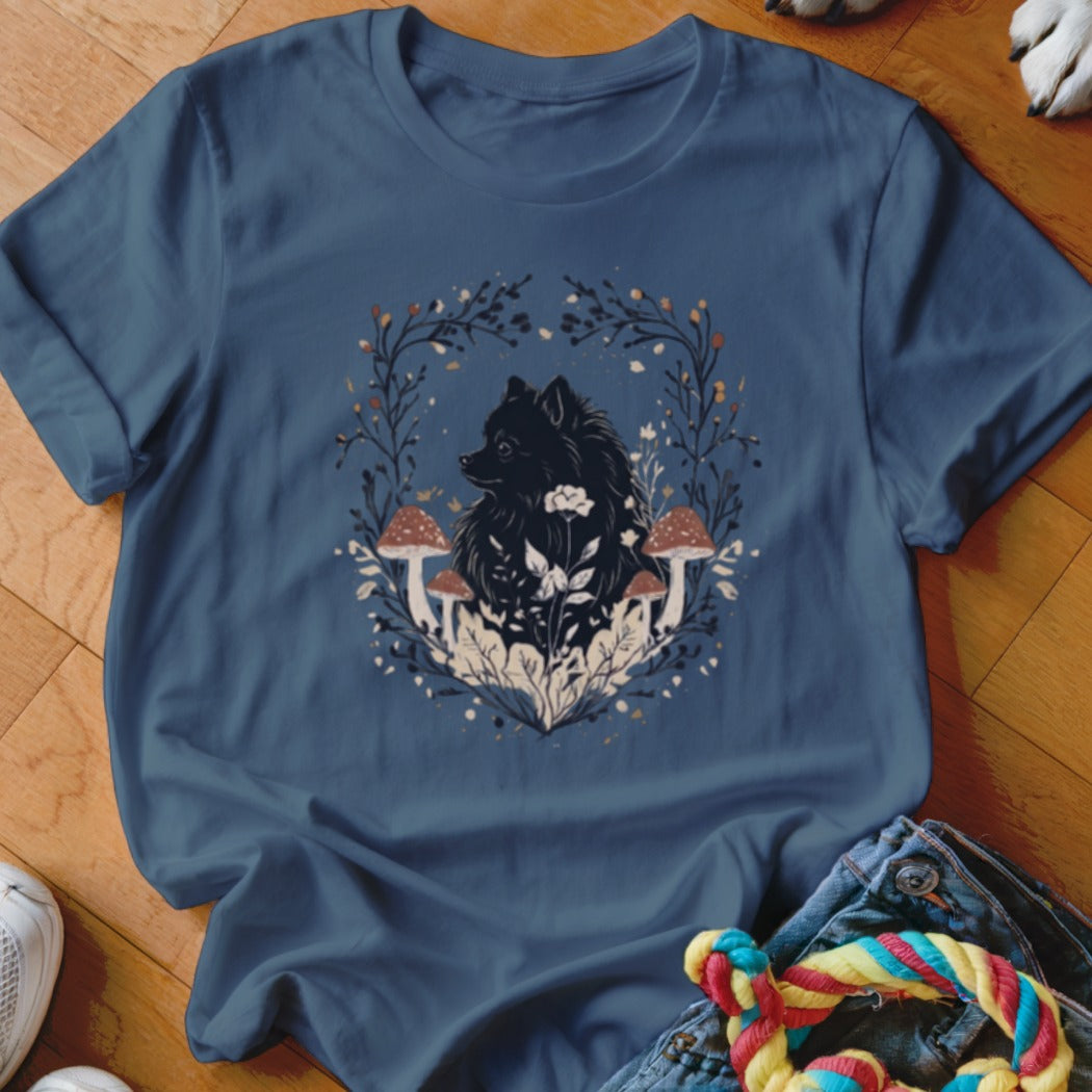 A blue t-shirt featuring a graphic of a black dog surrounded by mushrooms and leaves.