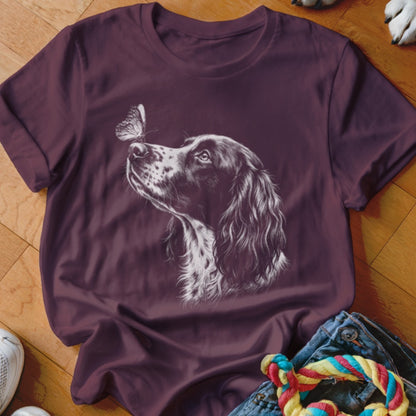 A dark purple t-shirt featuring a white line drawing of a spaniel dog looking at a butterfly on its nose.