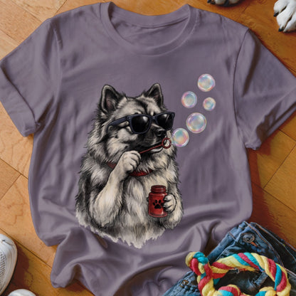 A purple t-shirt featuring a graphic of a fluffy dog wearing sunglasses and blowing soap bubbles.