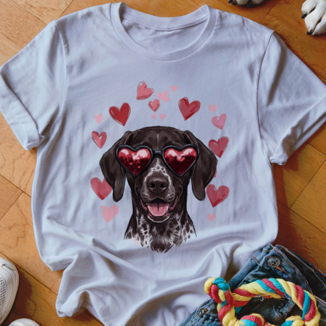 A white t-shirt featuring a graphic of a brown dog wearing heart-shaped sunglasses surrounded by pink hearts.
