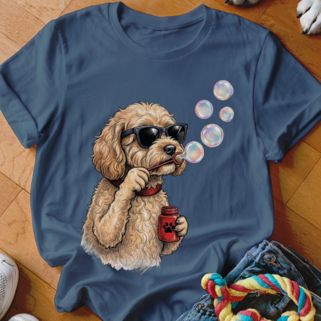 A dark blue t-shirt features a graphic of a fluffy, golden poodle wearing sunglasses and blowing bubbles.