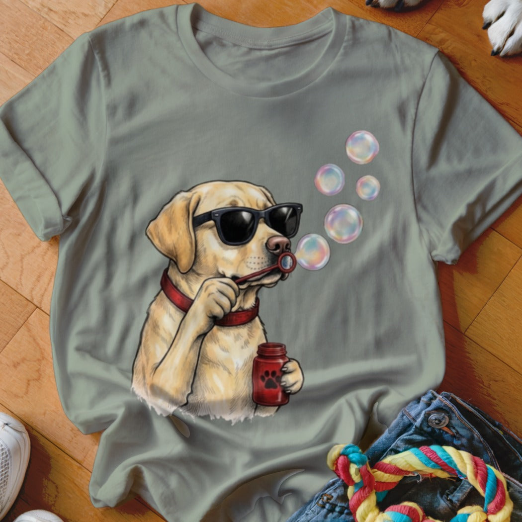 Sage green t-shirt featuring an illustration of a yellow Labrador wearing sunglasses and blowing soap bubbles.