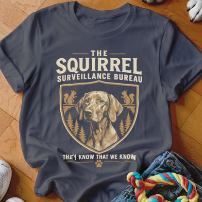 Dark grey t-shirt featuring a dog graphic, crest, trees, squirrels, and the text The Squirrel Surveillance Bureau.