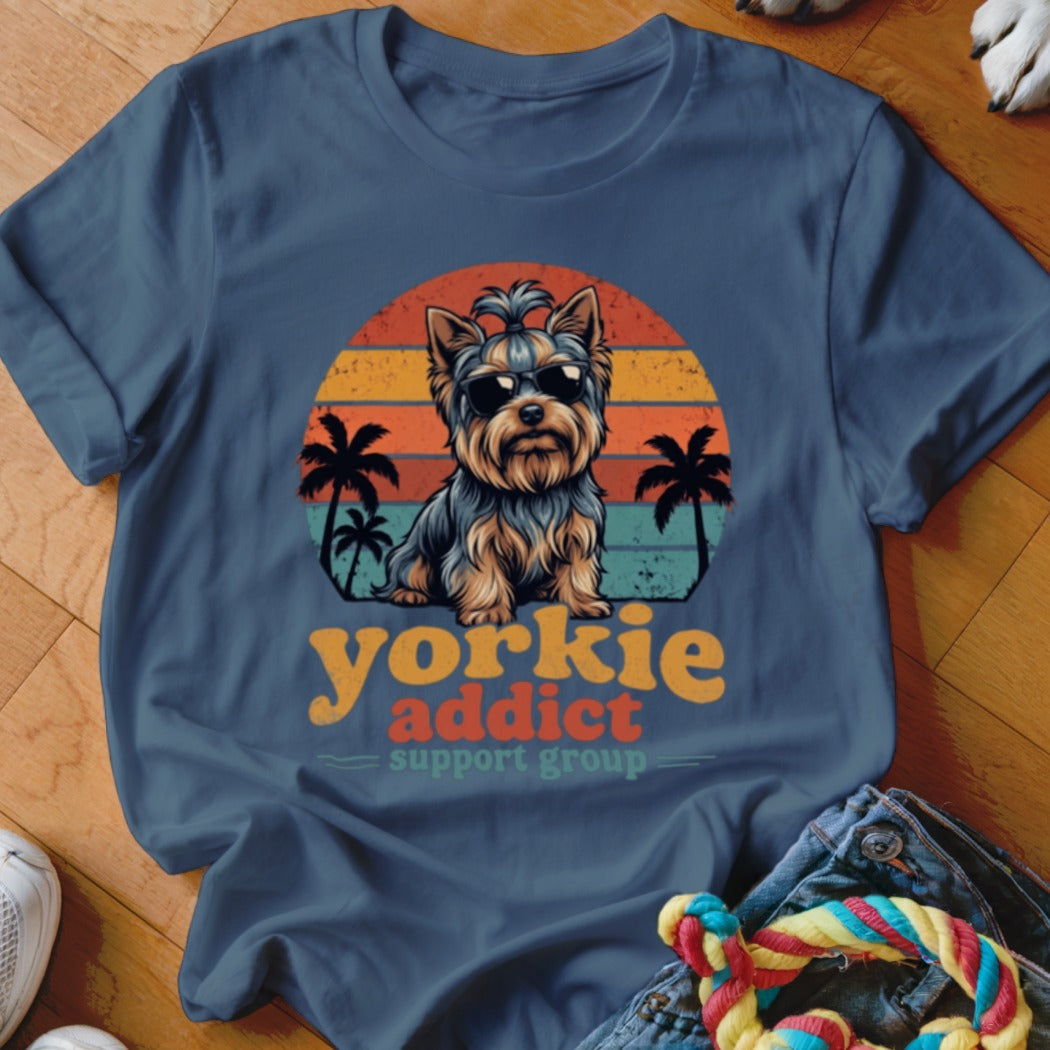 Blue t-shirt featuring a graphic of a Yorkshire Terrier wearing sunglasses in front of a retro sunset.