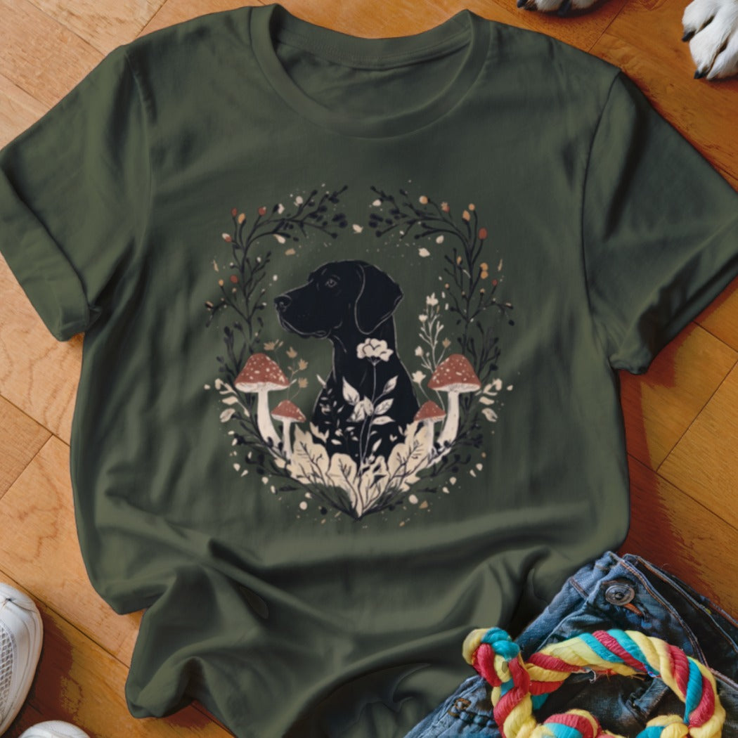 An olive green t-shirt featuring a black dog graphic surrounded by mushrooms and leaves.
