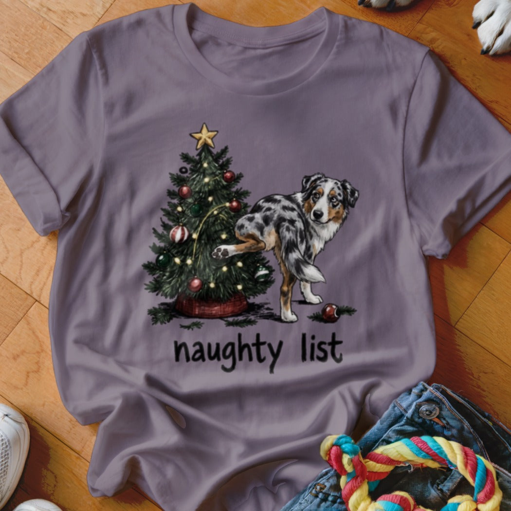Australian Shepherd dog near Christmas tree with text "naughty list."