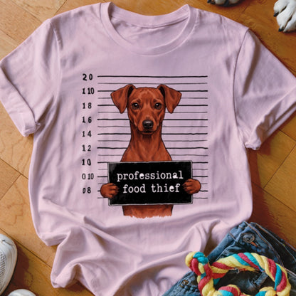 Pink t-shirt with a mugshot of a brown dog holding a sign that reads "professional food thief."