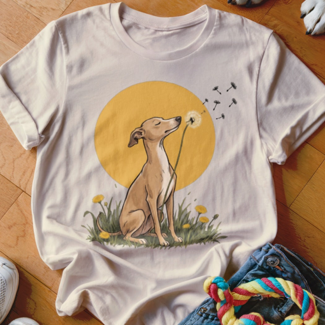Beige t-shirt featuring an illustration of a brown dog sitting in grass, blowing a dandelion.