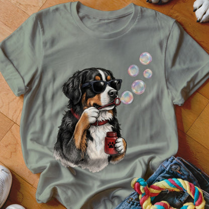 Sage green t-shirt featuring a graphic of a Bernese Mountain Dog wearing sunglasses and blowing bubbles.