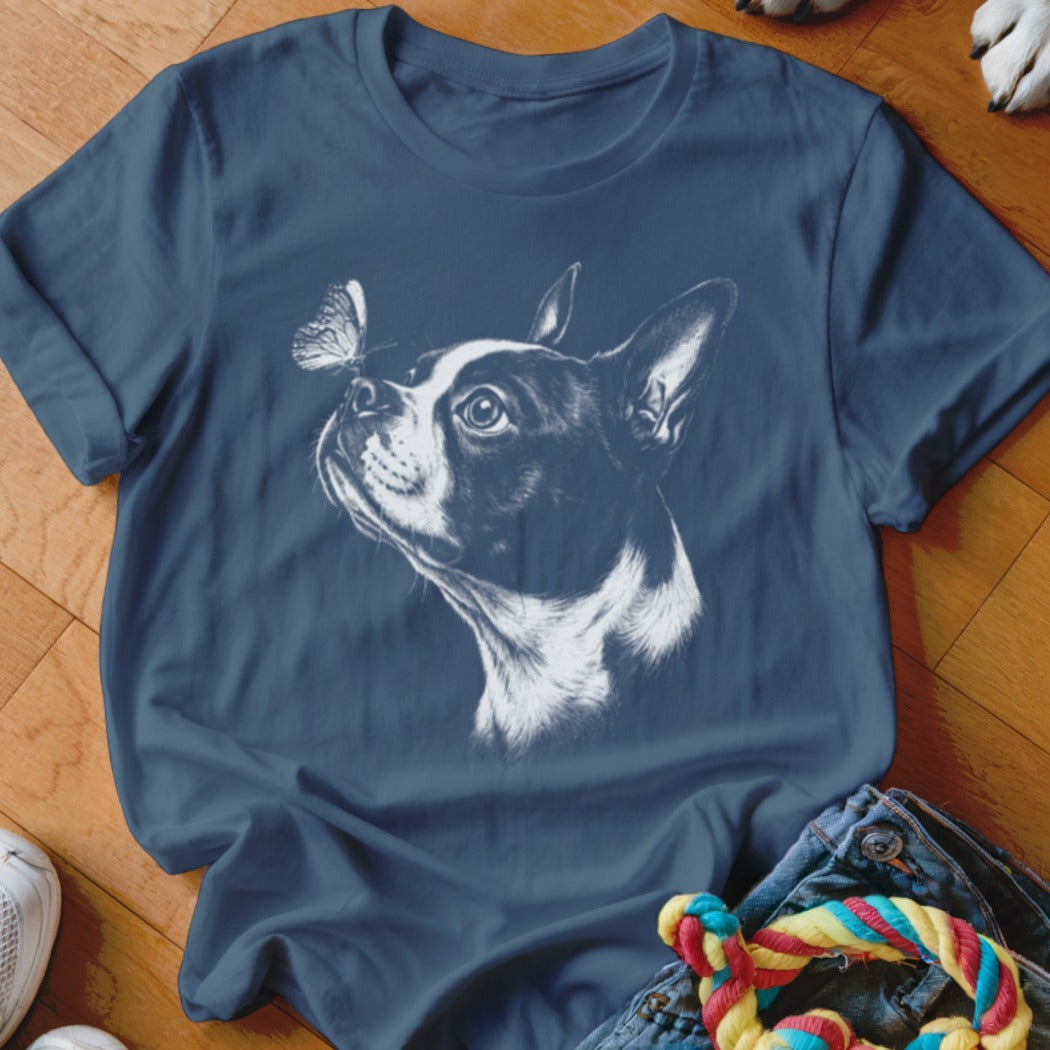A dark blue crewneck t-shirt featuring a white sketch of a Boston terrier looking at a butterfly on its nose.