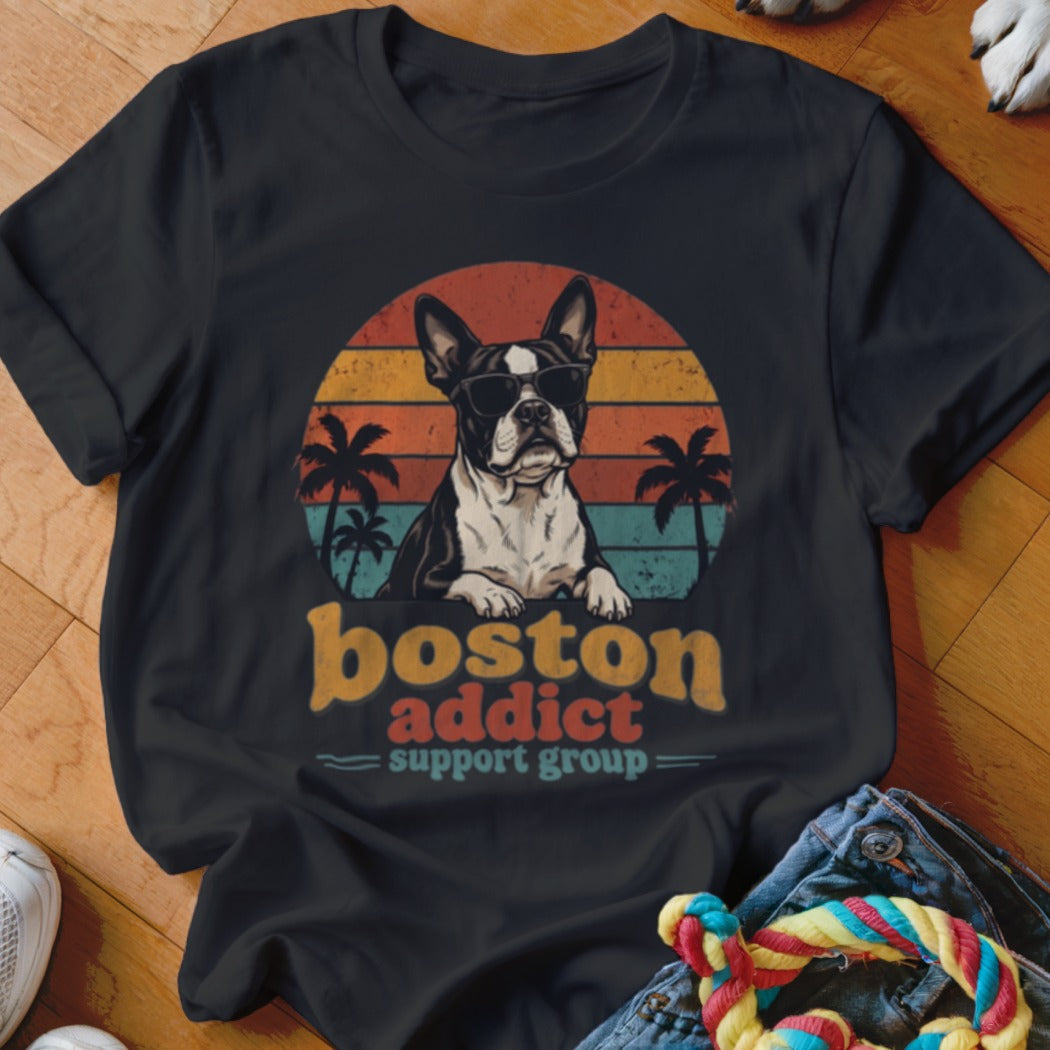 A black t-shirt features a graphic of a Boston Terrier in sunglasses against a retro sunset and palm trees, with the text boston addict support group.