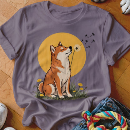 A grey t-shirt featuring a graphic of a Shiba Inu blowing dandelion seeds against a yellow circle background.
