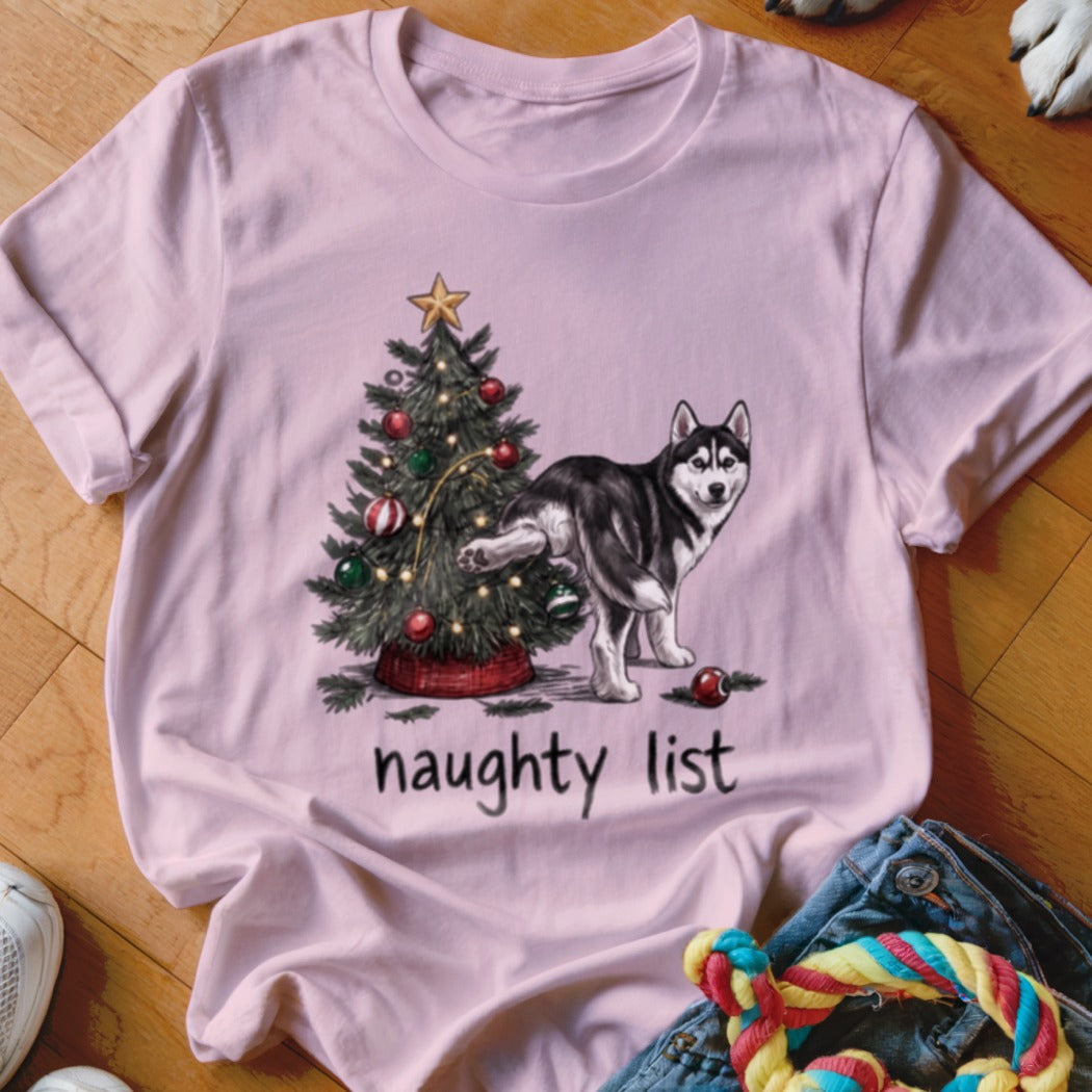 A light pink t-shirt features a husky peeing on a Christmas tree, with the text "naughty list".