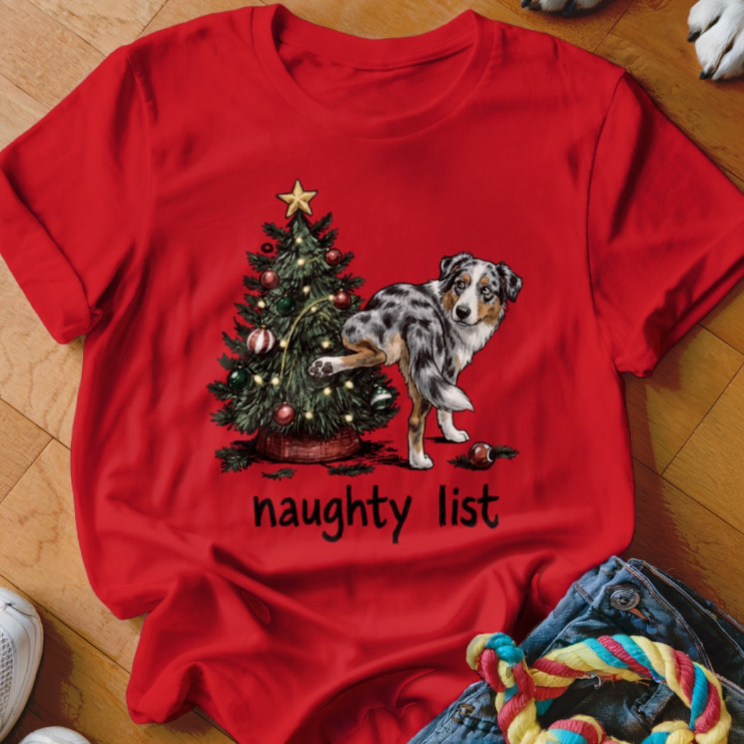 Red t-shirt with a drawing of a dog near a Christmas tree and the text "naughty list".