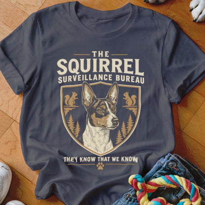 Dark grey t-shirt featuring a dog graphic, shield emblem, squirrels, and text reading The Squirrel Surveillance Bureau.