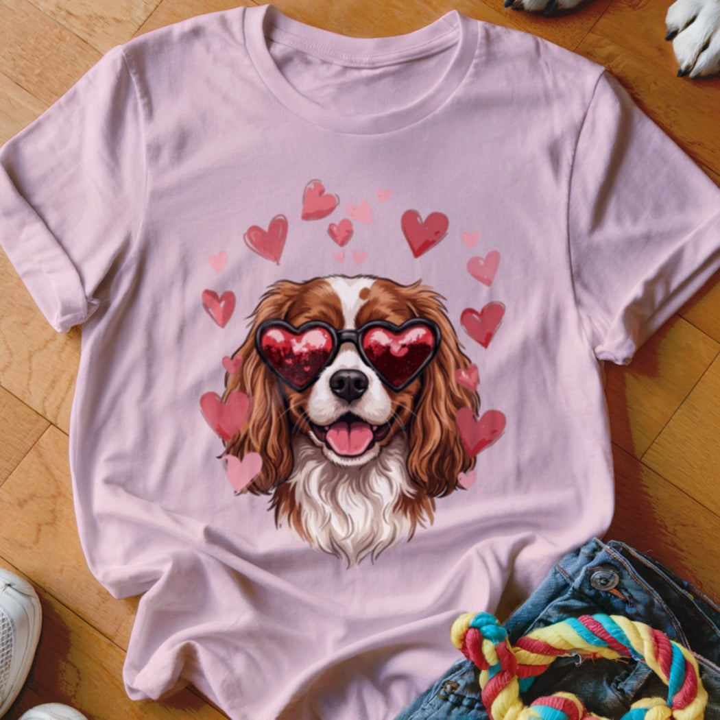 Light pink t-shirt featuring a graphic of a brown and white dog wearing heart-shaped sunglasses surrounded by pink hearts.
