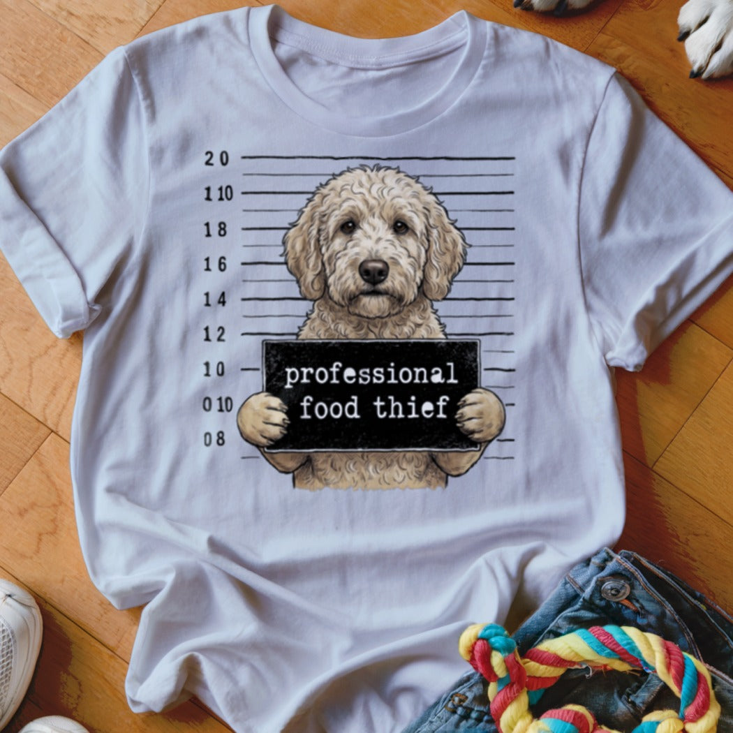 Goldendoodle mugshot with sign reading "professional food thief."