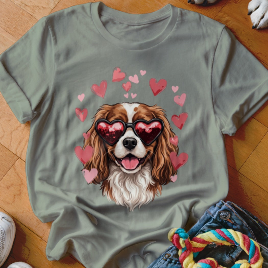 Sage green t-shirt featuring a Cavalier King Charles Spaniel graphic wearing heart-shaped sunglasses surrounded by pink hearts.