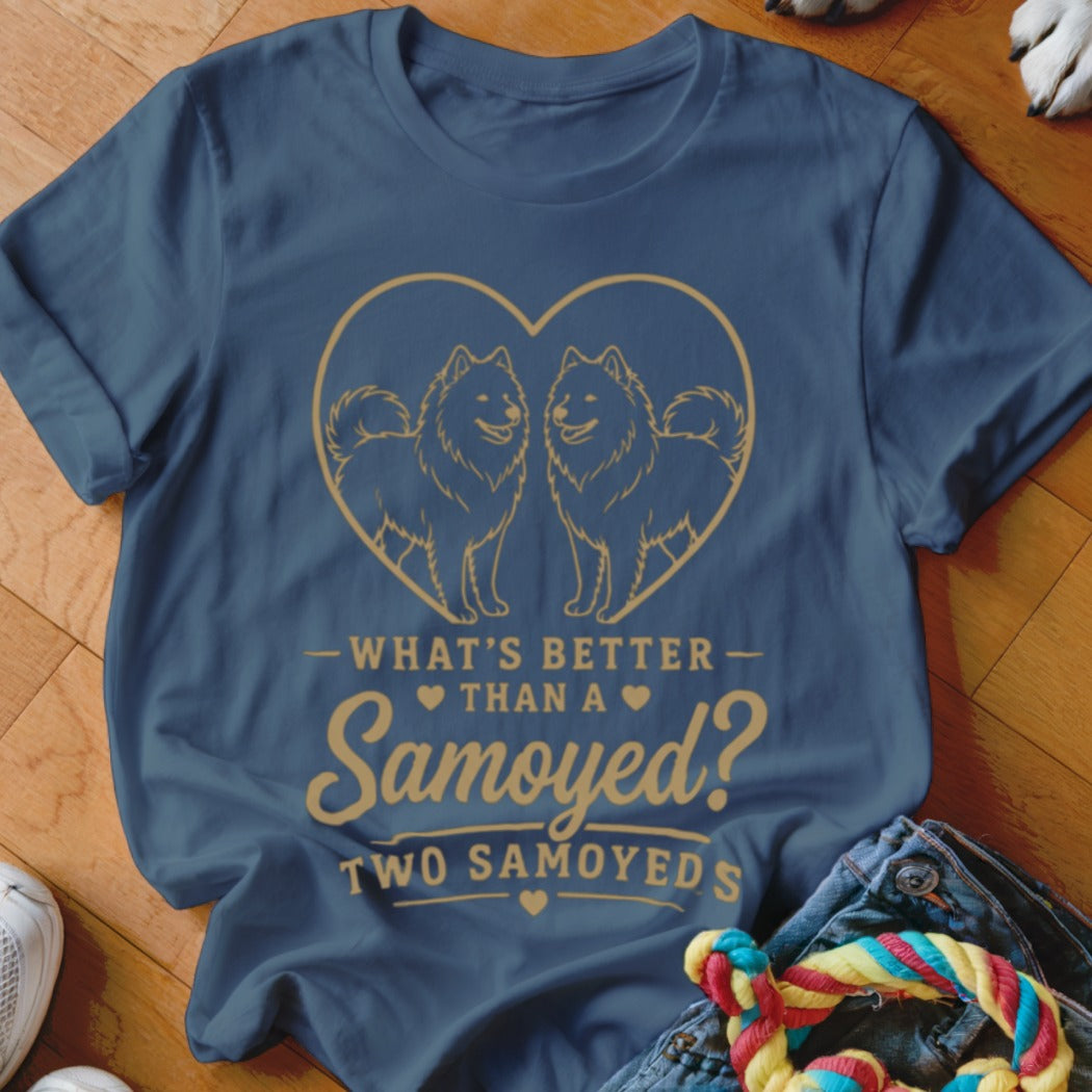 Blue t-shirt featuring a gold graphic of two Samoyed dogs inside a heart and the text What's Better Than A Samoyed? Two Samoyeds.