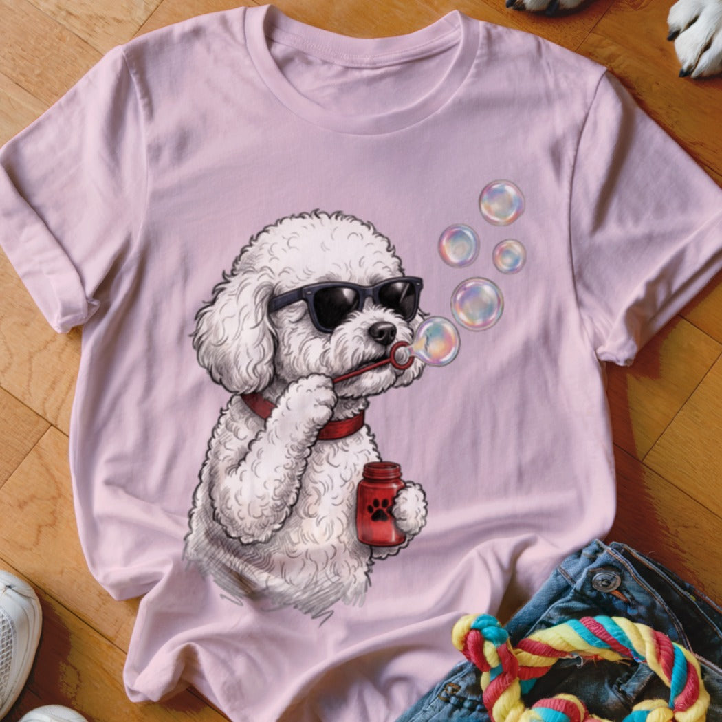 A light pink t-shirt featuring a graphic of a white poodle wearing sunglasses and blowing bubbles.